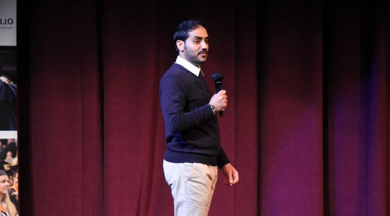 A man speaks on a stage.