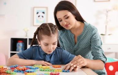 Young woman and little girl with autistic disorder playing a