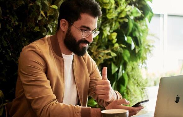 Man working on laptop giving thumbs up