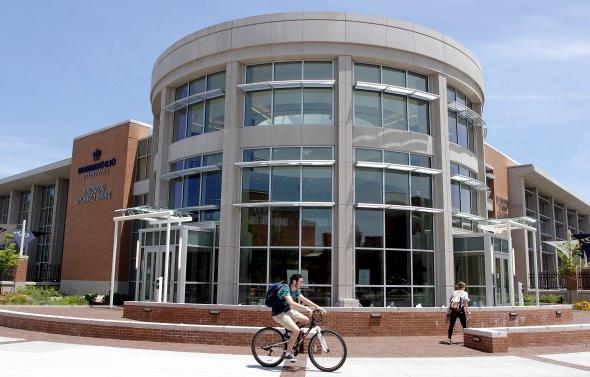 Student riding a bike in front of Broderick Dining Commons