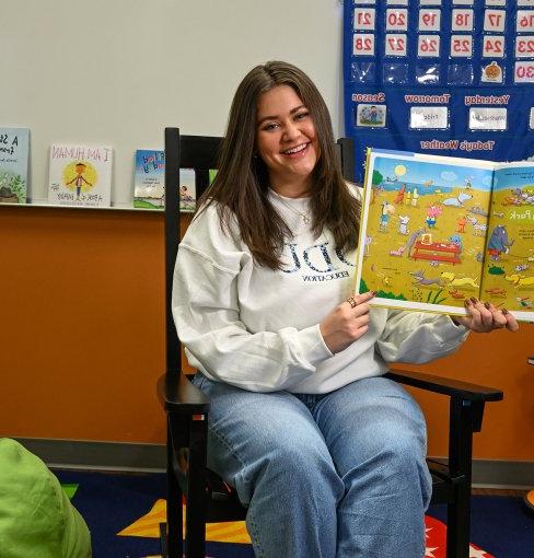 Teacher in classroom holding book